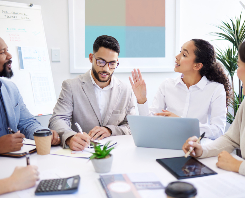 A group of people sitting around a conference table, discussing business matters and taking notes